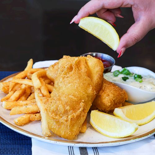 Crispy fried pastry served with a small bowl of dip and a lemon wedge on the side.