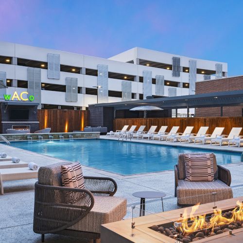 A snowy marina with wooden boats, small cabins, and a dock beside bright, clear water, under a blue sky.