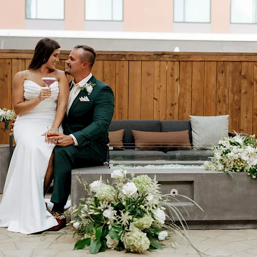 A bride and groom in a venue clink champagne glasses, smiling at each other during their wedding celebration.