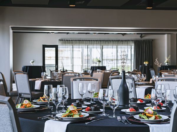 A dressed-up banquet table with sparkling wine glasses, plates of food, and a black champagne bottle in an elegant dining room.
